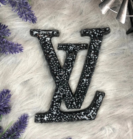 Black and silver LV logo on a textured surface with purple flowers.