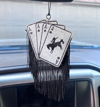 Decorative car hanging with playing card design and fringes on a car dashboard.
