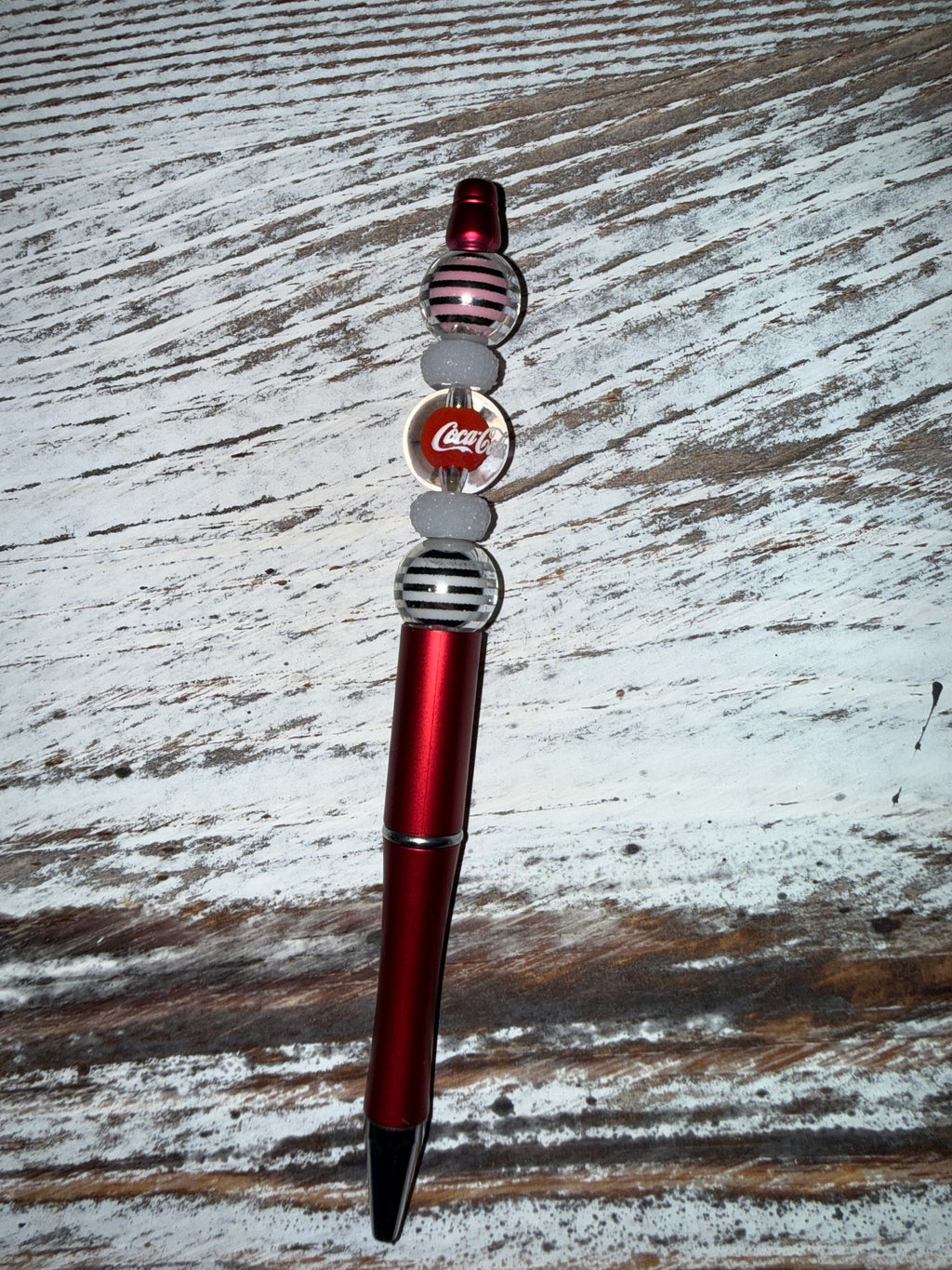 Decorative pen with Coca-Cola logo on a wooden surface