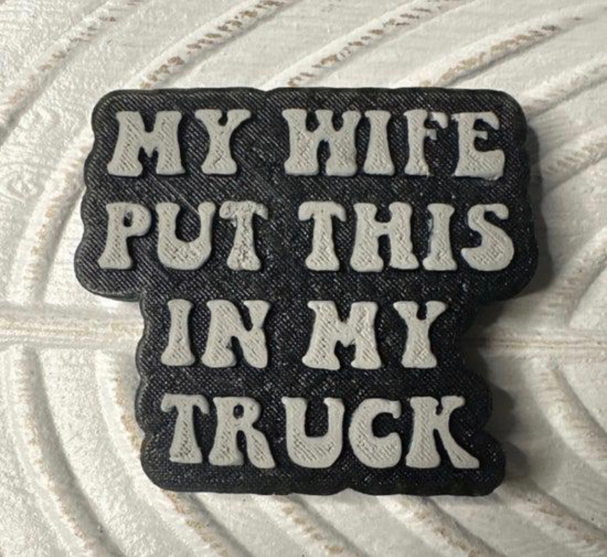 Black and white patch with text 'My wife put this in my truck' on a textured surface